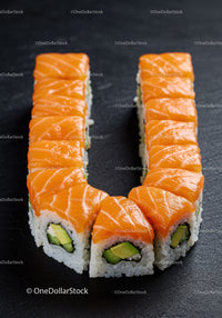 Fresh salmon avocado sushi arranged in U shape on slate
