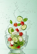 Refreshing cucumber and tomato salad splashing in glass bowl