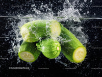Fresh Green Zucchini Splashed with Water Against Black Background