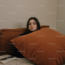 Young Woman Resting with Orange Cushions on Sofa in Cozy Interior