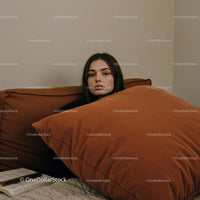 Young Woman Resting with Orange Cushions on Sofa in Cozy Interior