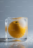 Fresh orange fruit frozen inside clear ice cube
