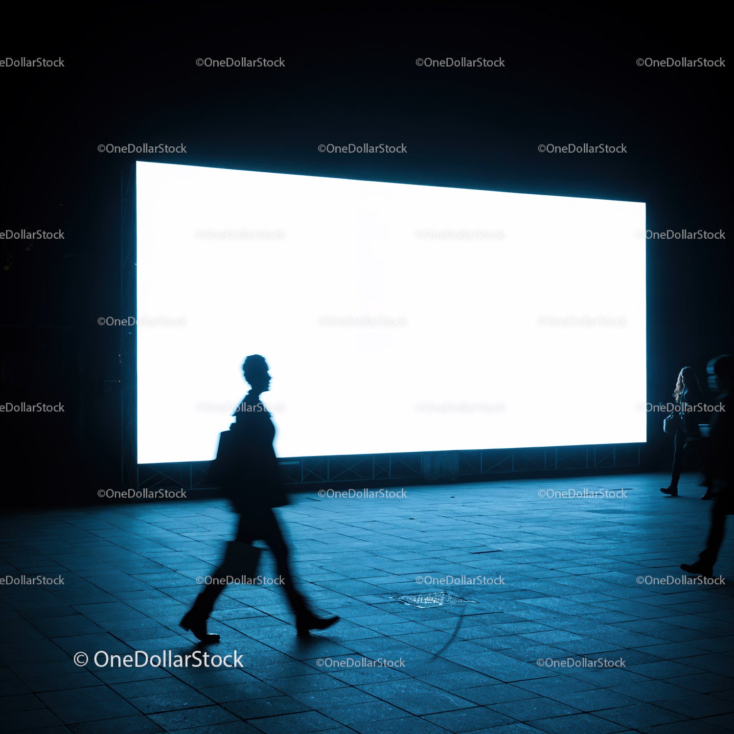 Silhouettes Walking Past Illuminated Urban Billboard at Night