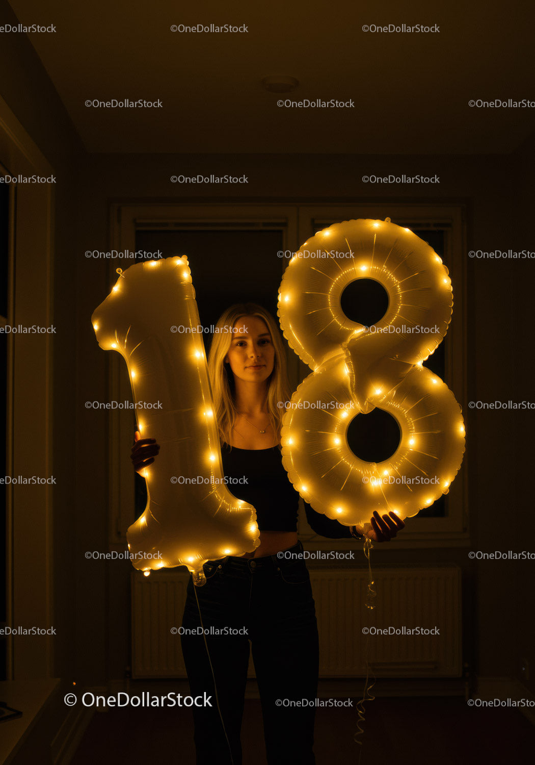 Young woman celebrating eighteenth birthday with illuminated balloons
