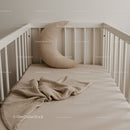 Minimalist baby crib with crescent moon pillow and blanket