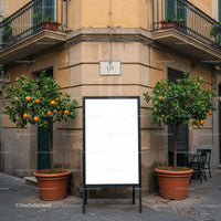Empty sidewalk sign between orange trees in urban street