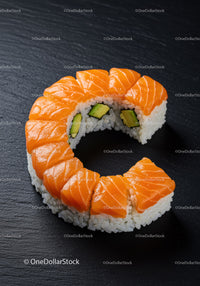 Fresh salmon avocado sushi roll on black slate plate