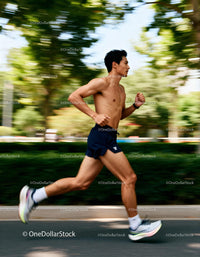 Shirtless man running fast along urban street path