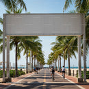 Cyclists and pedestrians along sunny palm-lined boardwalk