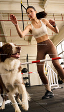 Active woman training her dog in indoor agility course
