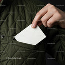 Person placing blank card into green quilted jacket pocket