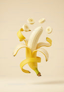 Fresh peeled banana with floating slices on beige background