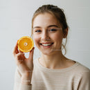 Young Smiling Woman Holding Orange Slice for Bright Summer Vibe