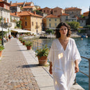 Woman in flowing white dress walking by waterfront town