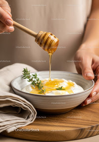 Honey Drizzling Over Yogurt with Fresh Thyme on Wooden Table