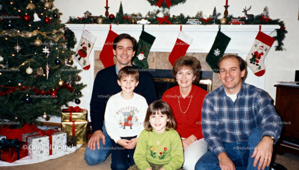 Family Gathered by Holiday Fireplace with Christmas Tree