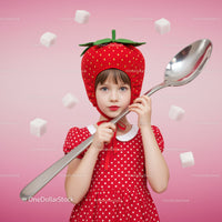 Little girl in strawberry hat holding giant spoon
