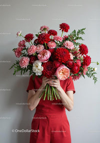 Person holding large bouquet of vibrant red and pink flowers
