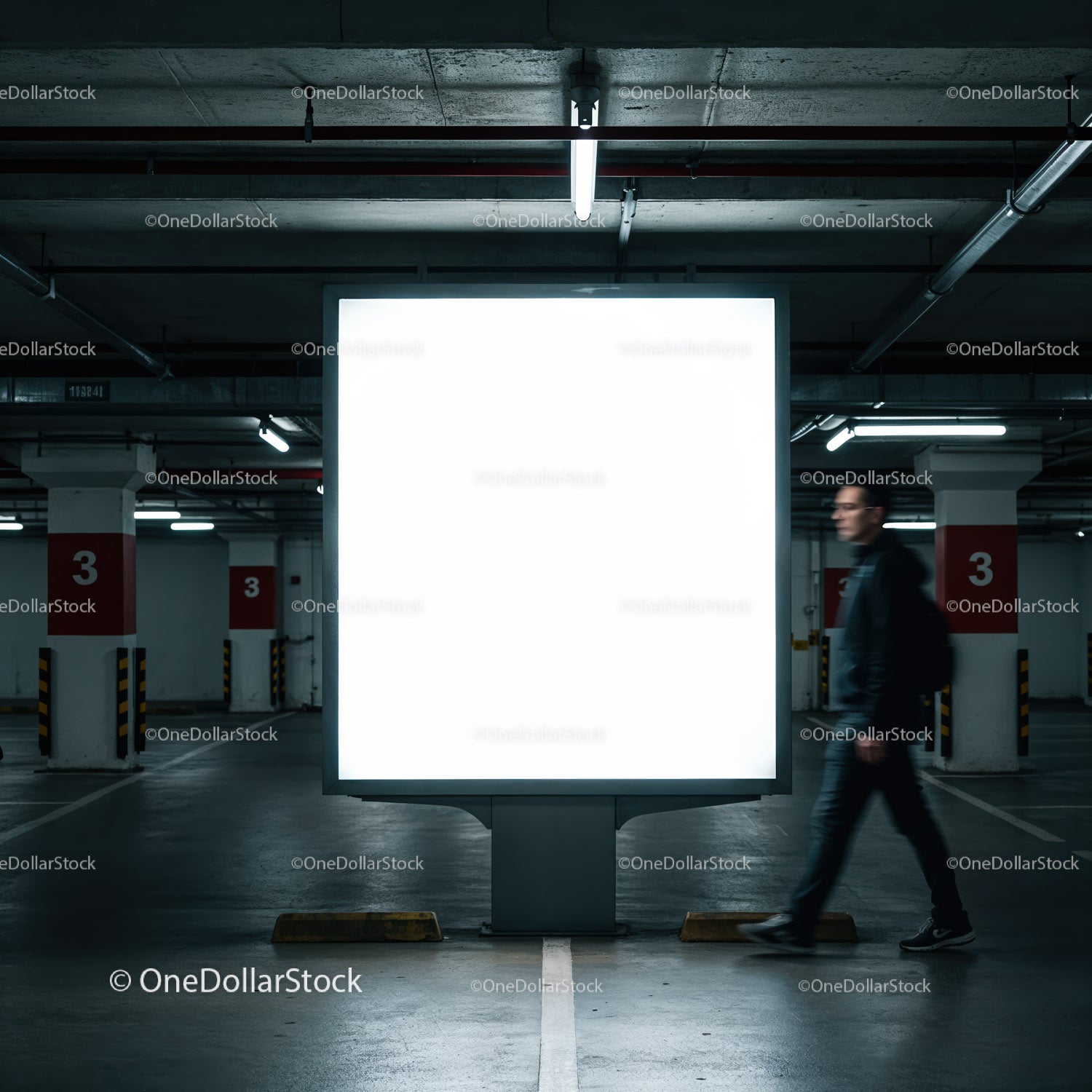 Mężczyzna przechodzący obok oświetlonego billboardu w garażu podziemnym