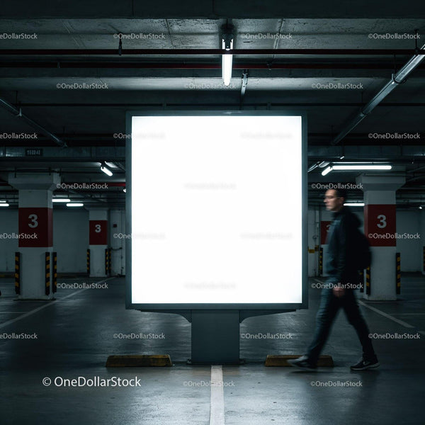 Man walking past illuminated billboard in underground garage JPG Mockup Image