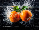 Fresh Orange Tangerines Splashing into Water with Green Leaves