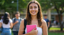 Young Smiling Woman with Pink Notebook Outdoors on Campus