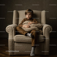 Young boy sitting with cozy knit blanket on armchair