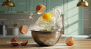 Fresh egg cracking into metal bowl with sugar cubes