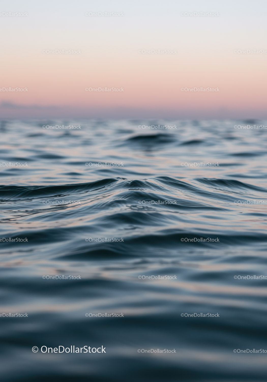 Spokojne fale oceanu o zachodzie słońca, różowe niebo i spokojna woda