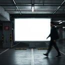 Blurred silhouette walking past blank billboard in underground parking