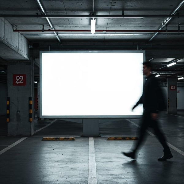 Blurred silhouette walking past blank billboard in underground parking JPG Mockup Image