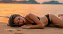 Glamorous woman lying on sandy beach during sunset