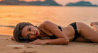 Glamorous woman lying on sandy beach during sunset