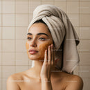 Young Woman with Towel on Head Applying Face Mask in Spa