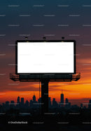 Empty illuminated billboard against city skyline at sunset