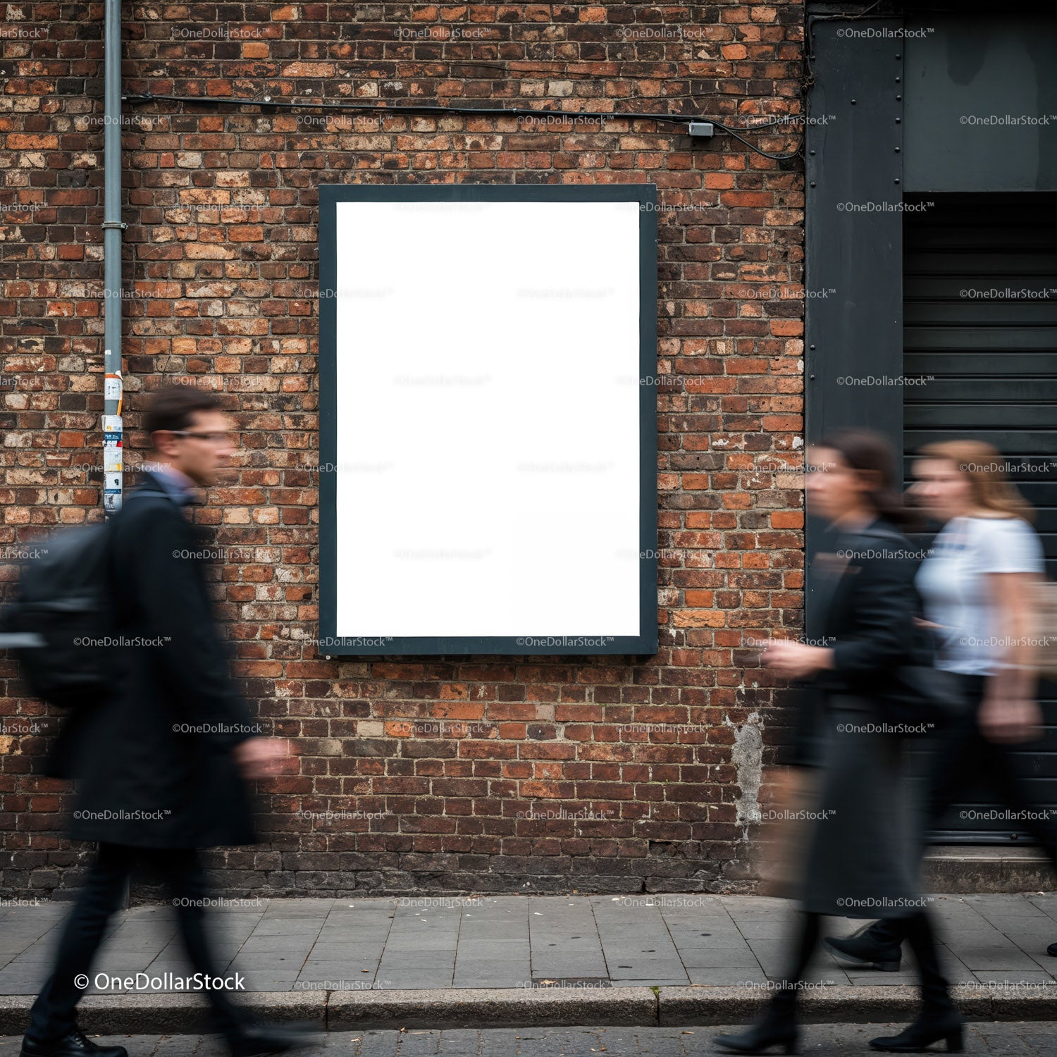 Blurred pedestrians walking past blank brick wall poster