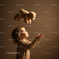 Child Reaching for Floating Teddy Bear with Wonder