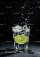 Refreshing lime slice splashing in sparkling water glass
