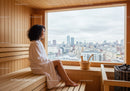 Woman Sitting and Relaxing in Sauna with City Skyline View