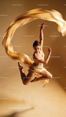 Graceful dancer in mid-air leap with flowing fabric