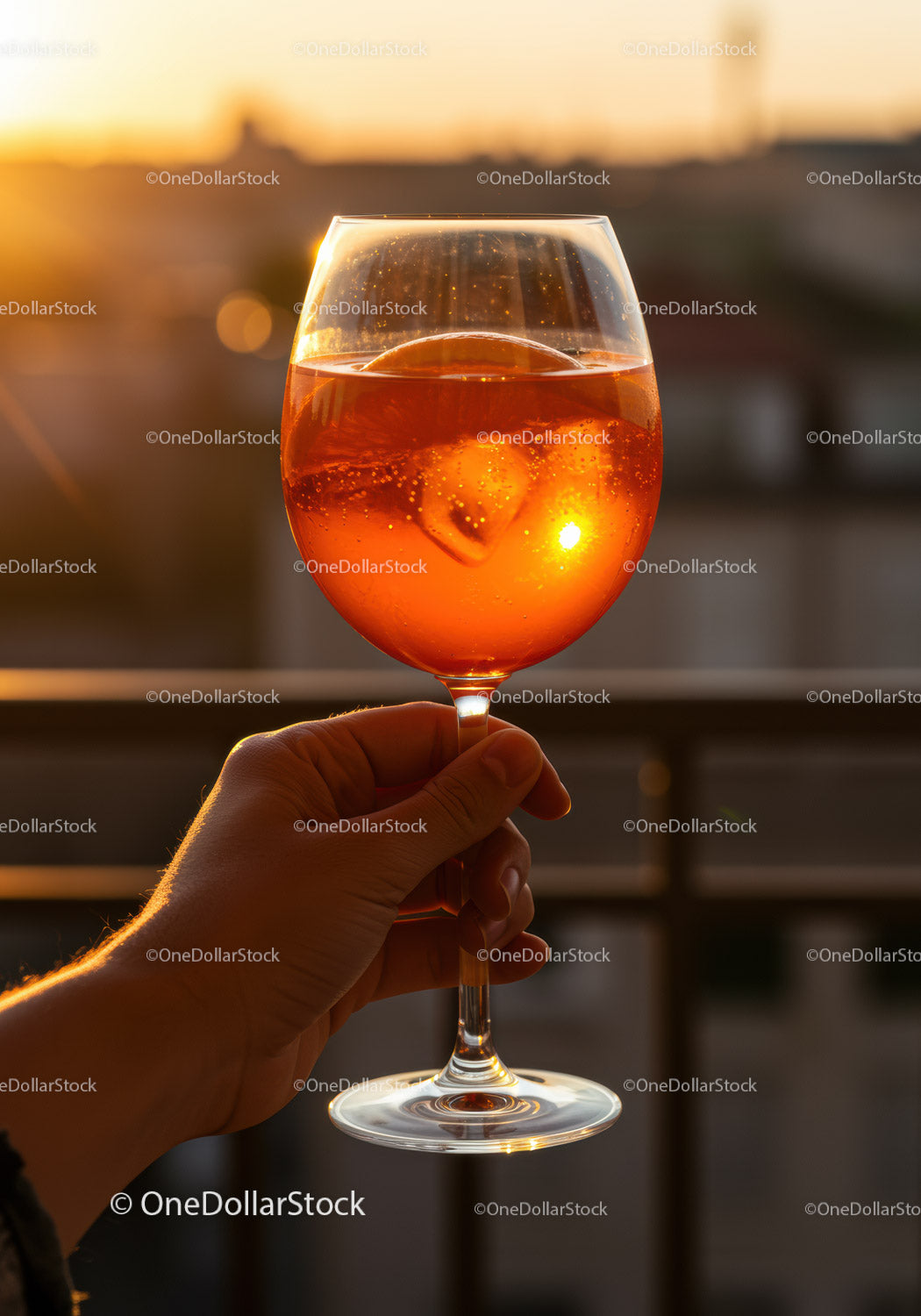 Dłoń trzymająca Aperol Spritz na tle złotego światła zachodzącego słońca