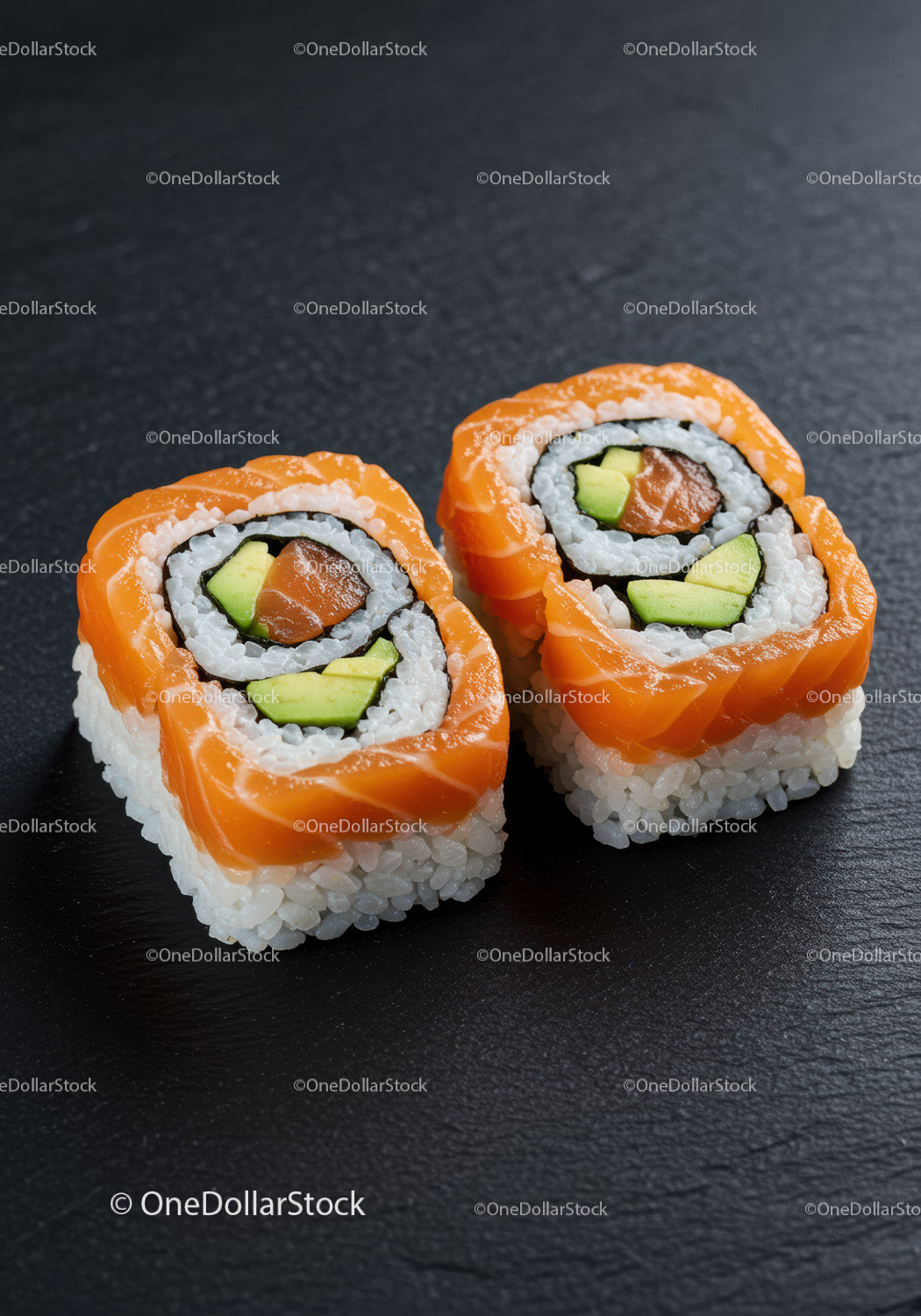 Fresh salmon avocado sushi rolls on dark slate plate