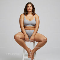 Confident Plus Size Woman Sitting on White Stool in Studio