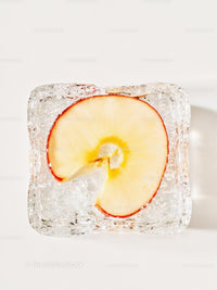Frozen apple slice trapped inside a clear ice cube