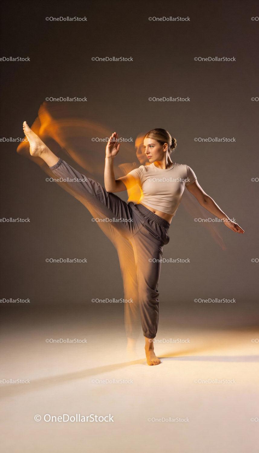 Focused woman practicing high kick in motion blur