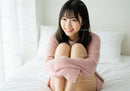 Young Woman Sitting on Bed in Cozy Pink Sweater in Bright Bedroom