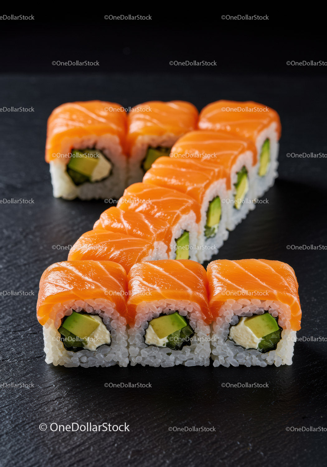 Fresh salmon avocado sushi rolls on black slate