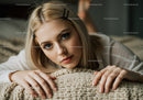 Young Woman with Blue Eyes and Blonde Hair in Cozy Indoor Setting