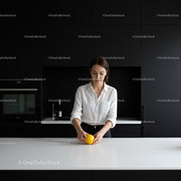 Woman in white shirt holding lemon in modern kitchen