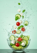 Fresh vegetable salad ingredients splashing in bowl